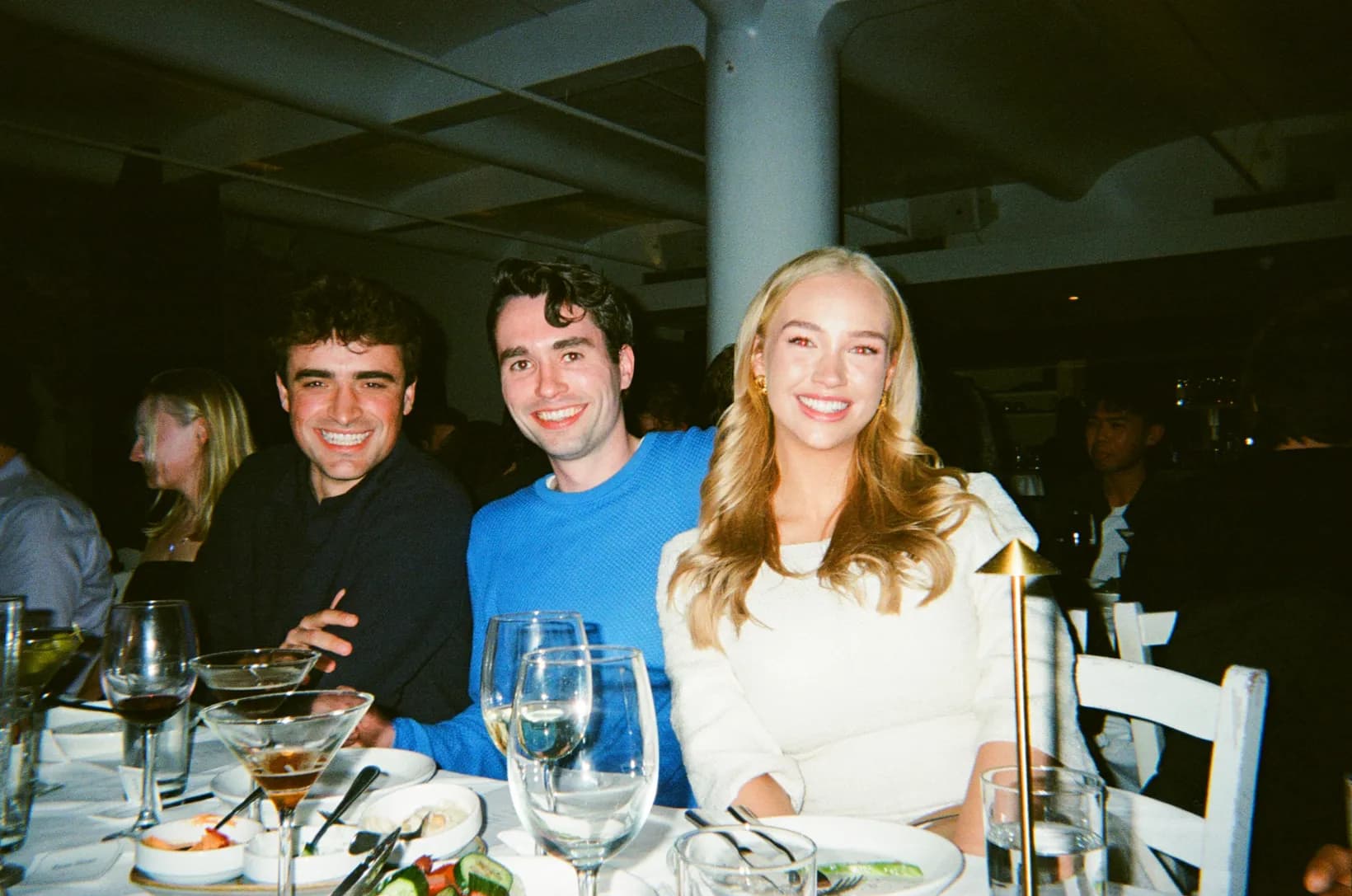 Three Rogo teammates smiling at a candlelit dinner table